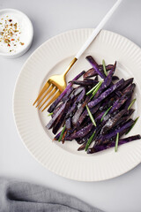 Plate with sticks of fried purple potatoes on light background, closeup