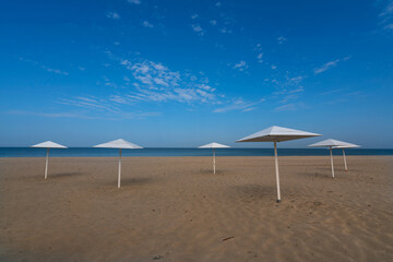 A deserted beach with wooden umbrellas on the shore of the Baltic Sea in the village of Yantarny, Kaliningrad region, Russia