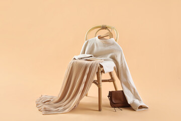 Chair with stylish clothes, book and bag on beige background