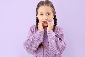 Little girl biting nails on lilac background, closeup