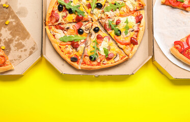 Cardboard boxes with tasty pizza on yellow background, closeup