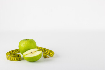 Green apple rolled up in measuring tape, symbolizing healthy life