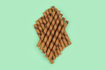 Heap of tasty wafer rolls on green background