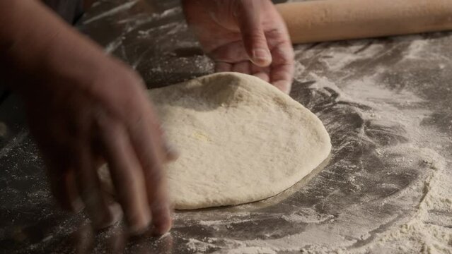 Rolling and kneading dough for flatbread baking, closeup on hands