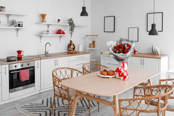 Interior of kitchen decorated for Valentine's Day with flowers, dining table and counters