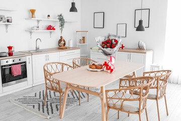 Interior of kitchen decorated for Valentine's Day with flowers, dining table and counters