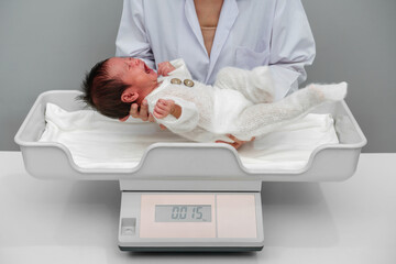 crying newborn baby weight measurement on digital scales with doctor in hospital