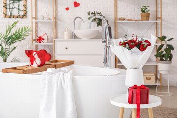 Vase with bouquet of flowers and gift on table in bathroom decorated for Valentine's Day