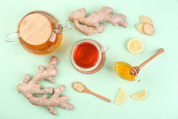 Ginger roots, cup of black tea, lemon and honey on mint background
