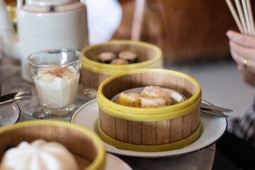 Steamed dumplings in freshly steamed baskets there stranded from the heat placed together Hot tea in a ceramic teapot, soft-boiled eggs in a glass, set apart and blurred around the table