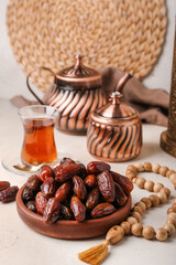 Bowl with dates and prayer beads for Ramadan on light table, closeup