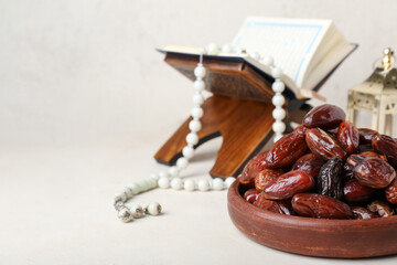 Bowl with dried dates for Ramadan on light table, closeup