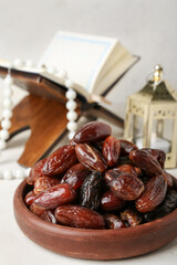 Bowl with dried dates for Ramadan on light table, closeup