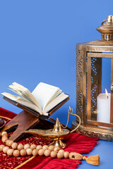 Aladdin lamp, prayer beads, Koran and Muslim lantern for Ramadan on blue background