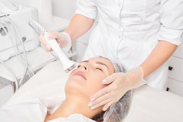 Cosmetologist makes ultrasound skin tightening for rejuvenation woman face using phonophoresis - obrazy, fototapety, plakaty