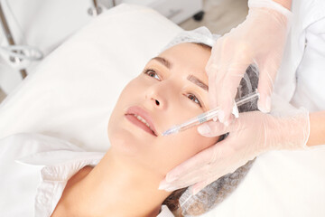 Cosmetologist makes fillers injection for lips augmentation and volume cosmetic procedure
