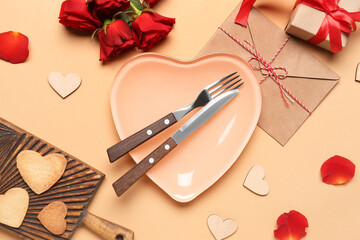 Fototapeta na wymiar Table setting with rose flowers and envelope on beige background. Valentine's Day celebration