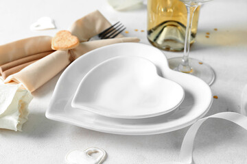 Heart-shaped plates and fork in napkin on white table. Valentine's Day celebration