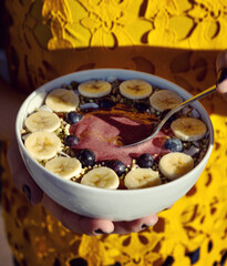 Acai smoothie Bowl with spoon yellow background