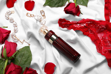 Perfume, jewelry, underwear and roses for Valentine's day on white fabric background