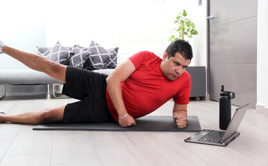 Overweight latina adult man exercises inside his home in his living room via computer online to be healthy