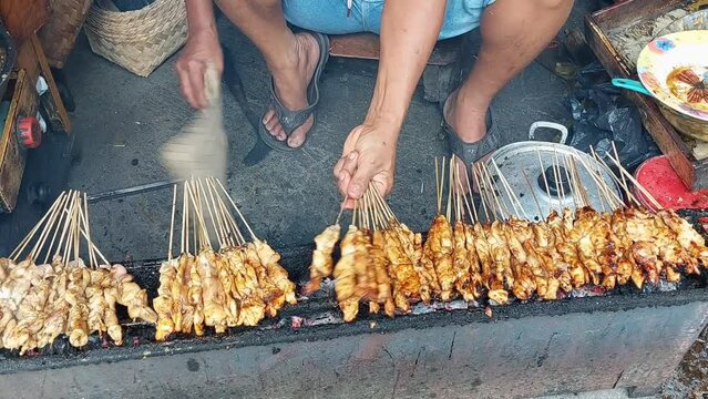 Sate ayam. a satay seller is grilling chicken satay over charcoal.  ponorogo satay is one of famous indonesian typical traditional food. 