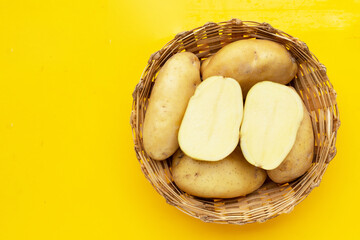 Raw potatoes isolated on yellow background.