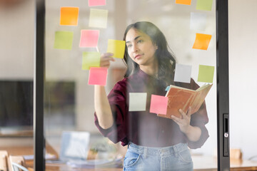 Business female employee with many conflicting priorities arranging sticky notes commenting and...