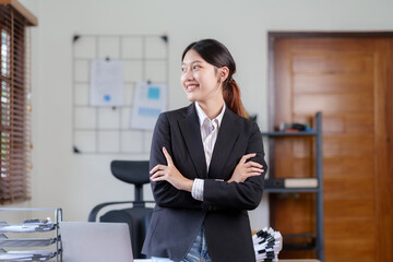 Beautiful and confident Asian businesswoman with arms crossed at office thinking of new ideas at work.