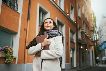 Business woman, tablet and thinking in the city of a freelance travel writer by buildings. Writing idea, technology and worker by a urban building with a happy smile about holiday traveling for work