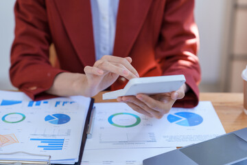 Close-up businesswoman using calculator to check job detail.