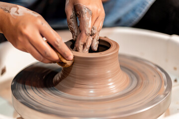 earthenware The art of sculpting clay with ceramics being molded by hand on a spinning machine. with the right posture to create a plate or vase professionally