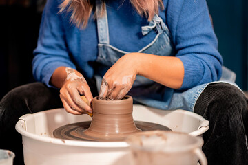 earthenware The art of sculpting clay with ceramics being molded by hand on a spinning machine. with the right posture to create a plate or vase professionally