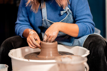earthenware The art of sculpting clay with ceramics being molded by hand on a spinning machine. with the right posture to create a plate or vase professionally