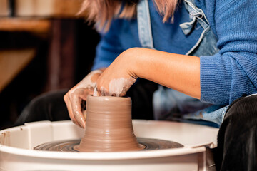 Fototapeta na wymiar earthenware The art of sculpting clay with ceramics being molded by hand on a spinning machine. with the right posture to create a plate or vase professionally