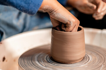 earthenware The art of sculpting clay with ceramics being molded by hand on a spinning machine. with the right posture to create a plate or vase professionally