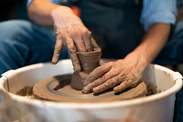 Close up male hands make a pot of clay in a pottery workshop. Potter's hands working clay on a potter's wheel