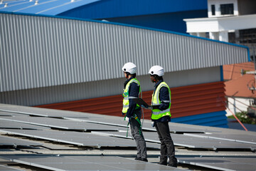 Well-equipped worker in protective clothing working and examining solar panels on a photovoltaic rooftop plant. Concept of maintenance and installation of solar station.