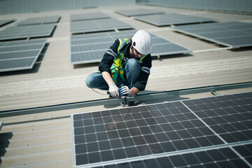 A worker is fixing solar panels on the roof. Engineer and technician using laptop checking and operating solar panels system on rooftop of solar cell farm power plant, Renewable energy source.