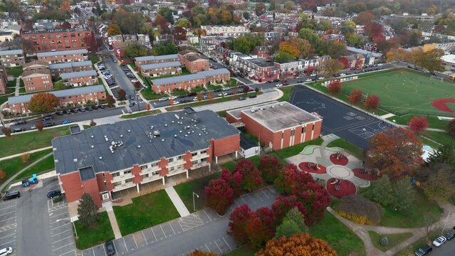 Aerial orbit around inner city elementary school in America. Autumn, fall covered leaves on school playground.