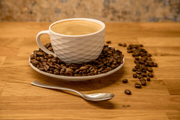 cup of coffee with coffee spoon and some beans on wooden table