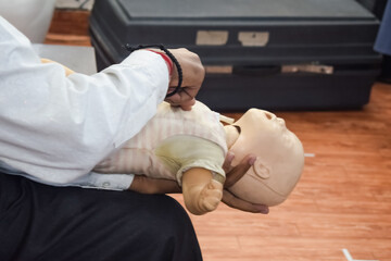 Man performing CPR on baby training doll dummy with one hand compression. First Aid Training - Cardiopulmonary resuscitation. First aid course on CPR dummy, CPR First Aid Training Concept
