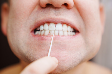 a man's mouth close-up. a man brush your teeth plastic toothpick with dental floss. concept of hygiene and health of teeth and oral cavity. daily care and brushing of teeth.