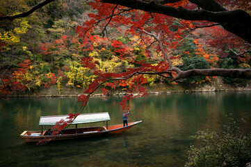 Traditional touris travel boat on the river in Kyoto city with autumn season background