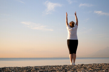 woman doing yoga performing asanas and enjoying life on the beach sea, sunset time