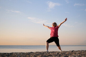 Obraz premium woman doing yoga performing asanas and enjoying life on the beach sea, sunset time