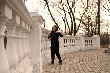 A girl with long hair is walking in the park. Beautiful warm sunset. A photo of a pretty young woman smiling at the wind in long curly brunette hair.