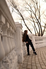 A girl with long hair is walking in the park. Beautiful warm sunset. A photo of a pretty young woman smiling at the wind in long curly brunette hair.