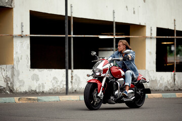 Naklejka premium Biker rides a motorcycle in an urban landscape.