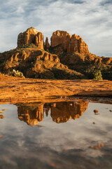 Fototapeta na wymiar Red rock cathedral rock illuminated during sunset reflecting on small natural pool in the american southwest of Sedona Arizona after a heavy rain fall